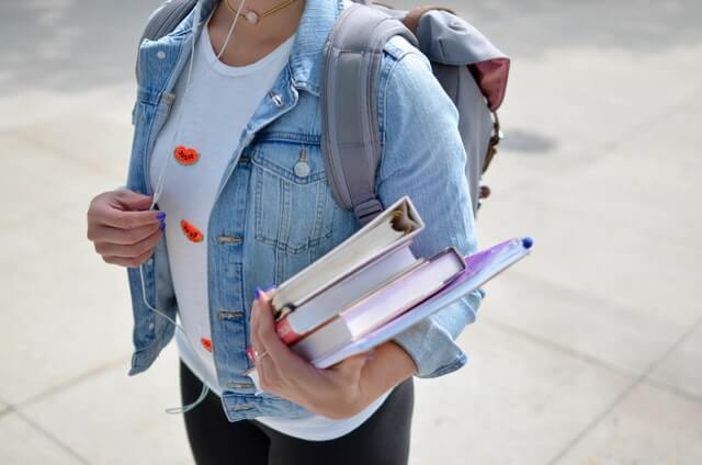Image of a female carrying books and a backpack
