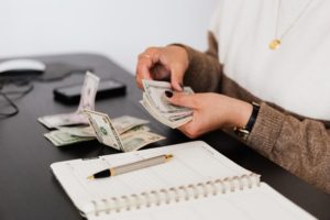 Image of woman counting money with a pen and notepad
