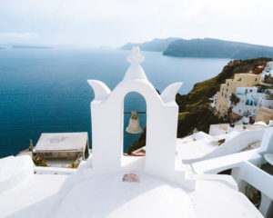 Image of white washed buildings in Santorini with a bell how to plan a trip to Europe