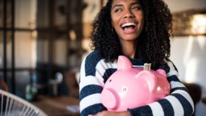 happy woman holding a pink piggy bank