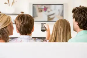 Image of a family watching tv - things to stop buying to save lots of money