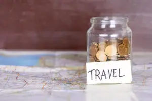 Image of Jar with change and note that reads travel - ways to save money on a tight budget