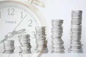 Image of increasing stacks of coins with a clock for ways to save money on a tight budget