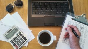 Image of desk with laptop, mug, calculator and papers