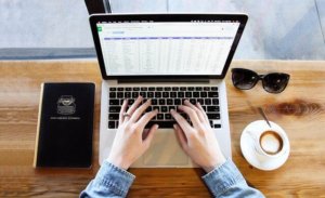 Image of hands typing on a computer to track expenses