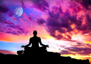 Pink and blue skies with person meditating with powerful money mantras