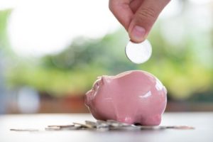 coin being dropped into small piggy bank